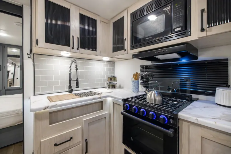 A travel trailer kitchen with a full stove, oven, microwave, and sink
